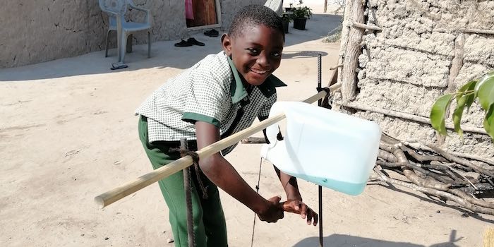 A young boy operates a tippy-tap.